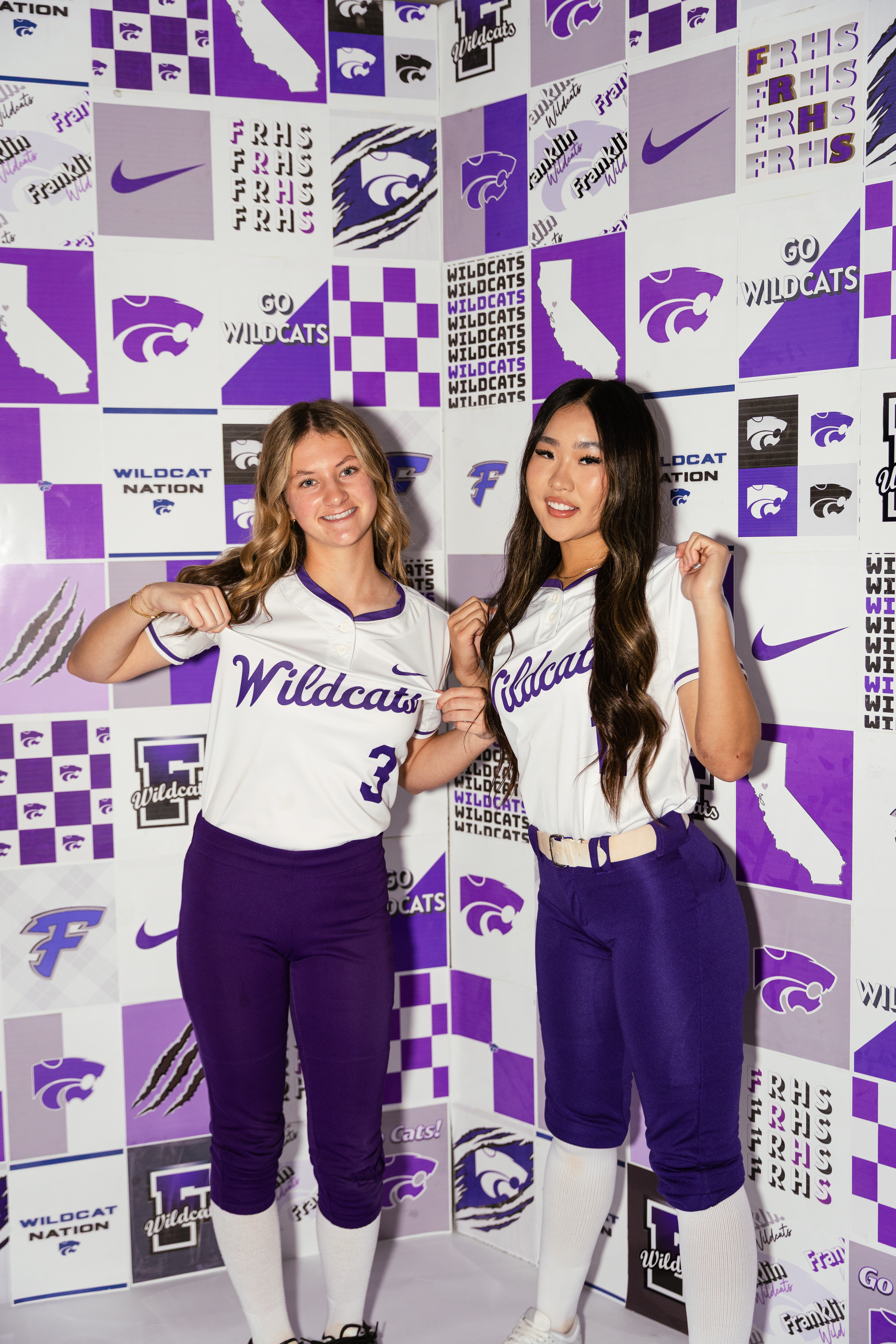 Softball duo in front of team banner